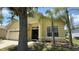 Inviting front exterior featuring a well-maintained lawn, palm trees, and a two-car garage at 954 Hacienda Cir, Kissimmee, FL 34741
