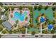 Aerial view of a community pool with umbrellas, a playground, a tiki hut, landscaping, and parking at 1000 Blackwolf Run Rd, Davenport, FL 33896