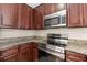 Modern kitchen with stainless steel appliances, granite countertops, and dark wood cabinets at 1208 Roma Ct, Orlando, FL 32825