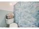 Close up of bathroom toilet and shower with blue tropical shower curtain and storage basket of towels at 1594 Frances St, Kissimmee, FL 34744