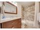 Bathroom with tiled shower and tub combination, brown wood vanity and framed mirror at 1594 Frances St, Kissimmee, FL 34744