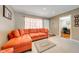 Cozy living room with an orange sofa, neutral carpeting, and bright natural light from the front door and window at 1594 Frances St, Kissimmee, FL 34744