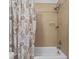 Close up on a clean bathroom with a full bathtub and shower combo with light beige tiling at 1809 Portofino Meadows Blvd, Orlando, FL 32824