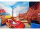 This 'Cars' themed room features custom mural, track car bed, and bright, cheerful design at 1817 Caribbean View Ter, Kissimmee, FL 34747