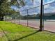 Outdoor tennis court enclosed by chain-link fence surrounded by green lawns at 2408 Barley Club Ct # 2, Orlando, FL 32837