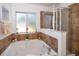 Bathroom showcasing a garden tub, a window, and a glass-enclosed shower at 2462 Hassonite St, Kissimmee, FL 34744