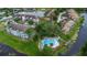 Aerial view of a community pool and waterfront with mature shade trees at 2662 Emerald Lake Ct, Kissimmee, FL 34744