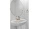 Modern powder room featuring a pedestal sink, oval mirror, and sleek fixtures at 3773 Deer Ridge Dr, Mount Dora, FL 32757