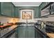 Kitchen with stainless steel appliances, dark countertops, and painted green cabinetry at 4820 Conway Rd # 130, Orlando, FL 32812