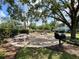Exterior common picnic area with stone picnic tables and charcoal grill nestled beneath mature trees at 4820 Conway Rd # 130, Orlando, FL 32812