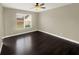 Bright living room with dark wood floors, ceiling fan, and a window with blinds at 4909 Terrapin Blvd, St Cloud, FL 34771