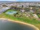 Aerial view of a community featuring a lakeside park with a playground, tennis courts, and basketball court at 550 Castlemain Cir, Davenport, FL 33897