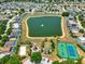 Drone shot of a community pond featuring a fountain, beach volleyball court, a tennis/basketball court, and green spaces at 550 Castlemain Cir, Davenport, FL 33897