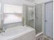Bright bathroom featuring a corner tub with jets, a clear glass shower, tile accents, and a gray rug at 639 Chadbury Way, Kissimmee, FL 34744