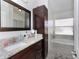 Bathroom with granite countertops, dark wood cabinets, a framed mirror and a separate tub at 639 Chadbury Way, Kissimmee, FL 34744