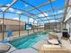 In-ground pool and spa with patio seating and a basketball hoop inside the screened pool enclosure at 639 Chadbury Way, Kissimmee, FL 34744