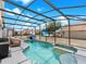 Enclosed in-ground pool featuring an attached spa, covered seating, a TV and a basketball hoop for recreation at 639 Chadbury Way, Kissimmee, FL 34744