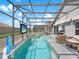 In-ground pool with spa, screened-in lanai, and patio seating and a TV for backyard entertainment at 639 Chadbury Way, Kissimmee, FL 34744