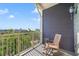 Exterior view of a sunny balcony overlooking lush greenery with a rocking chair and small table at 650 Campus St # 309, Celebration, FL 34747
