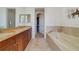 Bathroom featuring double sinks, granite counters, a large mirror, and a soaking tub at 650 Campus St # 309, Celebration, FL 34747