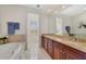Bathroom featuring double sinks, granite counters, a large mirror, and an adjacent room with shutters at 650 Campus St # 309, Celebration, FL 34747