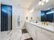 Bright bathroom featuring marble floors, double vanity with white cabinets, gold hardware, and a modern blue-tiled shower at 6514 Barnstorm Way, St Cloud, FL 34771