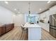 Bright kitchen with white cabinetry, stainless appliances, large center island, and wood-style flooring at 6514 Barnstorm Way, St Cloud, FL 34771