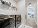 Modern laundry room with front-load washer and dryer, shelving, and marble flooring at 6514 Barnstorm Way, St Cloud, FL 34771