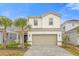 Inviting two-story home featuring a two-car garage, palm trees and a well-maintained brick paver driveway at 7211 Oakmoss Loop, Davenport, FL 33837