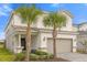 Charming two-story home with a two-car garage, palm trees, and manicured landscaping at 7211 Oakmoss Loop, Davenport, FL 33837