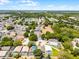 Sweeping aerial perspective of a neighborhood near a scenic lake featuring an expansive green space and mature trees at 829 Clear Creek Cir, Clermont, FL 34714