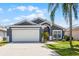 Charming single-Gathering home featuring a two-car garage, well-maintained lawn, and a beautiful palm tree in the front yard at 829 Clear Creek Cir, Clermont, FL 34714