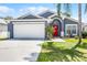 Charming single-story home featuring a vibrant red front door and well-maintained landscaping and an attached garage at 829 Clear Creek Cir, Clermont, FL 34714