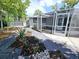 Backyard landscape with stone walkway, leading to a screened-in patio at 905 W 11Th Ave, Mount Dora, FL 32757