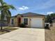 Charming single-story home featuring a red front door, attached garage, and well-maintained landscaping at 352 Madina Cir, Davenport, FL 33837