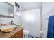 Bathroom with decorative vanity, silver framed mirror, and tiled shower with a white curtain at 1007 Maya Ave, Orlando, FL 32822