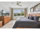 Bright main bedroom showcasing a tranquil lake view through a large window, complete with a ceiling fan and neutral tones at 1014 Umbria Dr, Kissimmee, FL 34759
