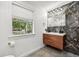 Modern bathroom with floating wood vanity, marble accent wall, and window view at 1104 E Anderson St, Orlando, FL 32801