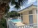 Community pool with a white fence, surrounded by palm trees, and a clubhouse at 13226 Galicia St # 103, Orlando, FL 32824