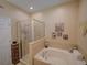 Well-lit bathroom showcasing a separate glass-enclosed shower and a soaking tub, complemented by tiled walls at 1416 Lexington Ave, Davenport, FL 33837