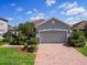 Charming home exterior with landscaped lawn, brick driveway, and a gray two-car garage at 1416 Lexington Ave, Davenport, FL 33837