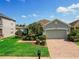 Well-manicured front yard featuring lush landscaping, a brick driveway, and a two-car garage at 1416 Lexington Ave, Davenport, FL 33837