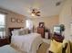 Comfortable main bedroom features a bed with decorative pillows, ceiling fan, and dresser with decorative mirror at 1416 Lexington Ave, Davenport, FL 33837