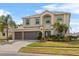 Two-story stucco home featuring a three-car garage, manicured lawn, and beautiful landscaping at 2005 Pitch Way, Kissimmee, FL 34746