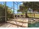 Tranquil seating area next to a screened-in pool and spa, overlooking a serene pond at 2005 Pitch Way, Kissimmee, FL 34746