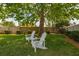 Tranquil backyard featuring two Adirondack chairs beneath a mature tree, creating an inviting outdoor retreat at 239 King George Dr, Davenport, FL 33837