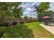 Large backyard with lush green grass, manicured hedges, and a stone patio with an outdoor dining set at 239 King George Dr, Davenport, FL 33837