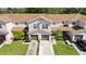 This is an aerial view of a townhouse with a two-car garage, driveway, green lawn, and landscaping at 3071 Seaview Castle Dr, Kissimmee, FL 34746