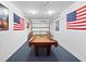 This spacious game room has a pool table with a wall-mounted garage door and patriotic decor at 3071 Seaview Castle Dr, Kissimmee, FL 34746