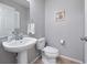 A neutral-toned half bathroom features a pedestal sink, a toilet, and a framed picture on the wall at 3071 Seaview Castle Dr, Kissimmee, FL 34746